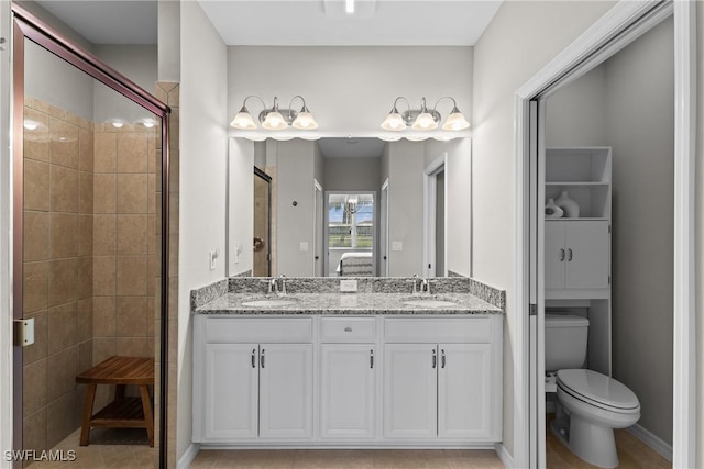 bathroom with double vanity, a sink, toilet, and a shower stall