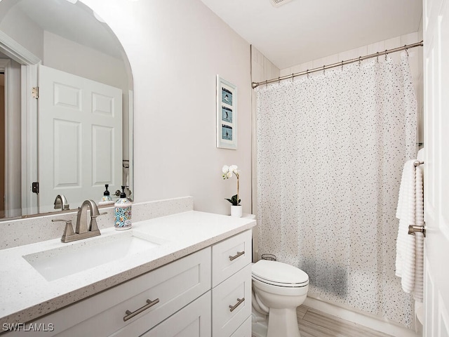 bathroom featuring a shower with shower curtain, toilet, and vanity