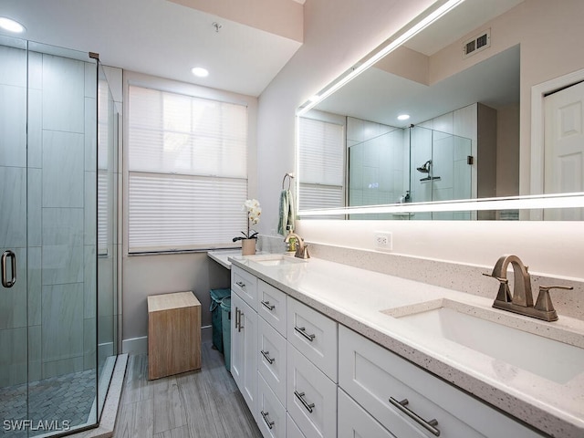 full bath with double vanity, visible vents, a shower stall, and a sink