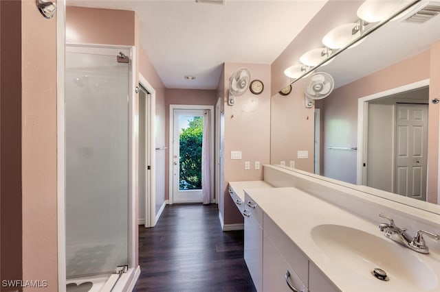 full bath with visible vents, a stall shower, wood finished floors, baseboards, and vanity