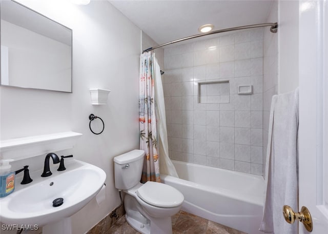 bathroom featuring toilet, shower / tub combo with curtain, and a sink