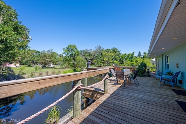 view of dock with a deck with water view and outdoor dining area