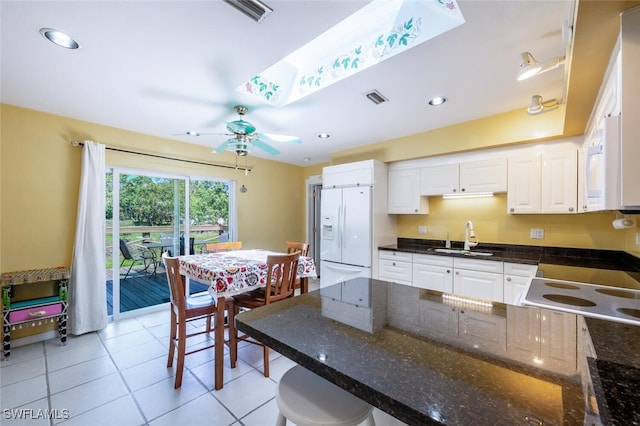 kitchen featuring white appliances, visible vents, a peninsula, a sink, and white cabinets