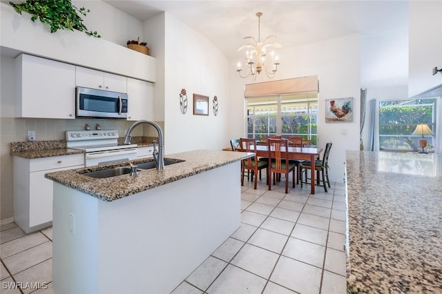 kitchen with stainless steel microwave, light tile patterned floors, electric range, white cabinetry, and a sink