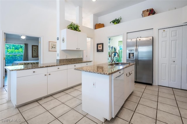 kitchen with stainless steel fridge with ice dispenser, light tile patterned floors, stone counters, white dishwasher, and white cabinetry