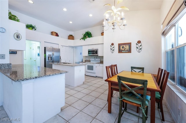 kitchen featuring a kitchen island, appliances with stainless steel finishes, white cabinets, a peninsula, and a chandelier