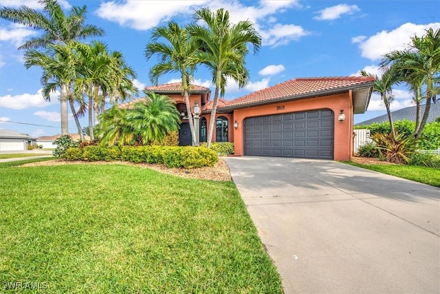 mediterranean / spanish house featuring an attached garage, a tile roof, concrete driveway, stucco siding, and a front lawn