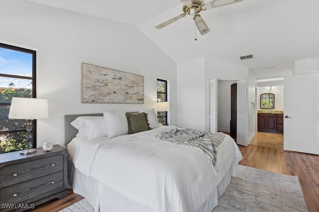 bedroom with visible vents, connected bathroom, ceiling fan, vaulted ceiling, and wood finished floors