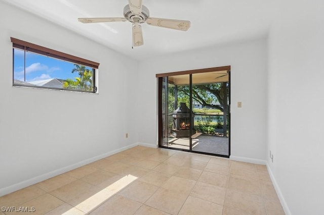 empty room with light tile patterned floors, a ceiling fan, and baseboards