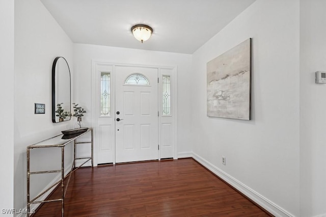 foyer featuring baseboards and dark wood finished floors