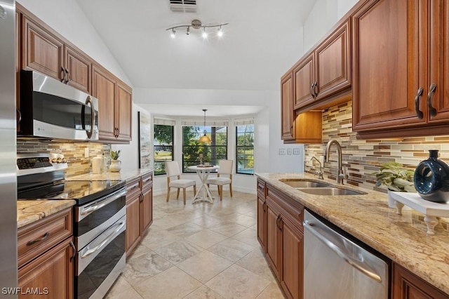 kitchen featuring visible vents, light stone countertops, lofted ceiling, stainless steel appliances, and a sink