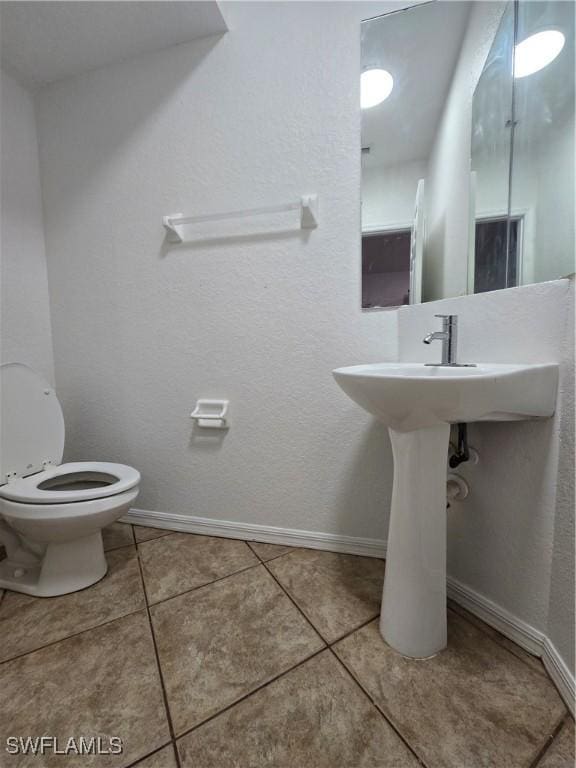 bathroom with tile patterned flooring, baseboards, and toilet