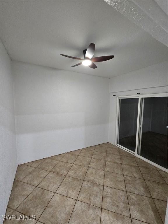 tiled spare room with ceiling fan