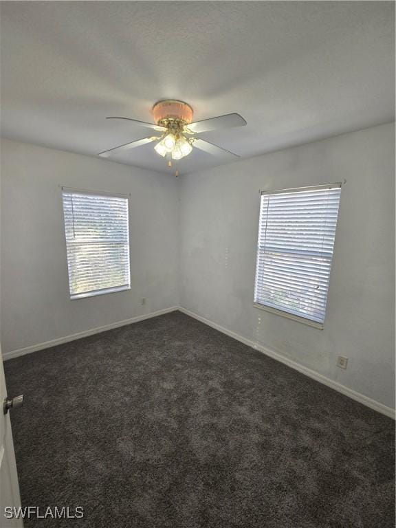 unfurnished room with dark carpet, a ceiling fan, and baseboards