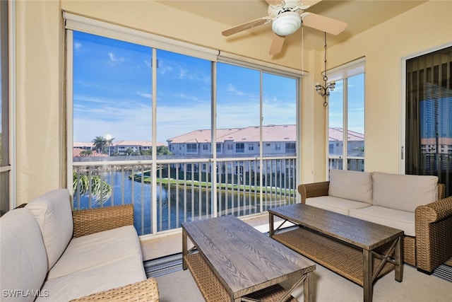 sunroom featuring a residential view, a water view, and ceiling fan