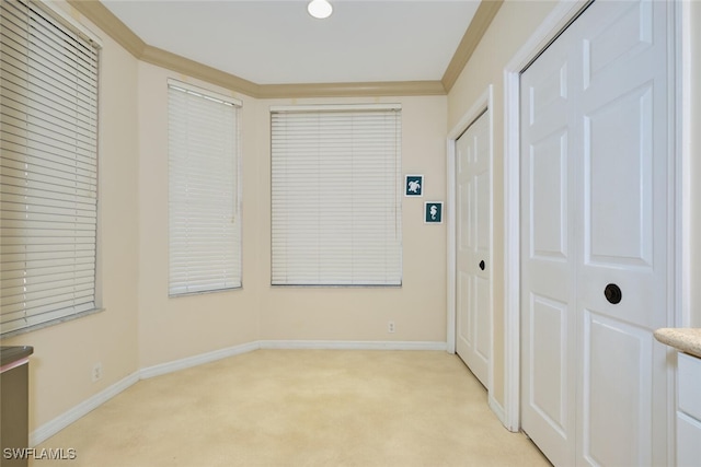 interior space featuring ornamental molding, light colored carpet, and baseboards