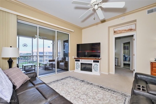 living room with ceiling fan, carpet floors, visible vents, baseboards, and ornamental molding