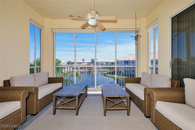 sunroom / solarium featuring a ceiling fan and a water view