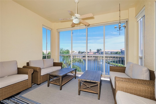 sunroom featuring a water view and ceiling fan with notable chandelier