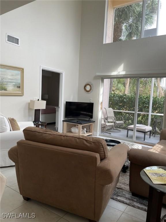 living room with light tile patterned floors, visible vents, and a towering ceiling