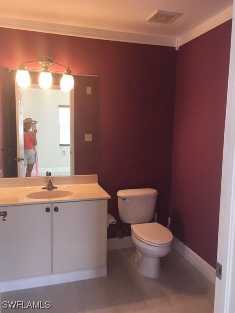 bathroom with vanity, baseboards, visible vents, tile patterned floors, and toilet