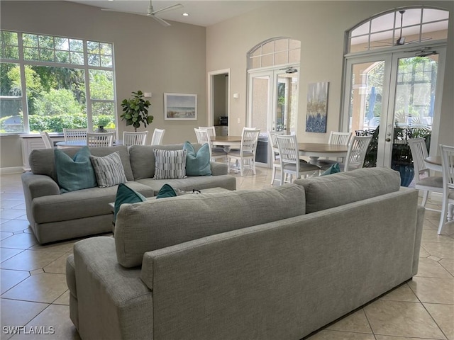 living area featuring a high ceiling, light tile patterned floors, a healthy amount of sunlight, and french doors