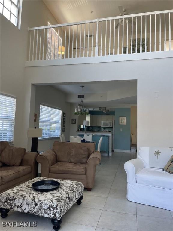 living area featuring light tile patterned floors, a healthy amount of sunlight, and a high ceiling