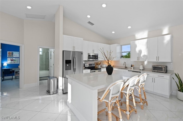 kitchen with visible vents, a sink, a kitchen island, white cabinetry, and stainless steel appliances