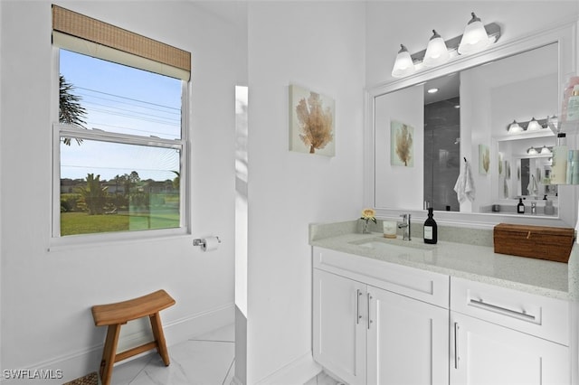 bathroom with marble finish floor, a walk in shower, vanity, and baseboards