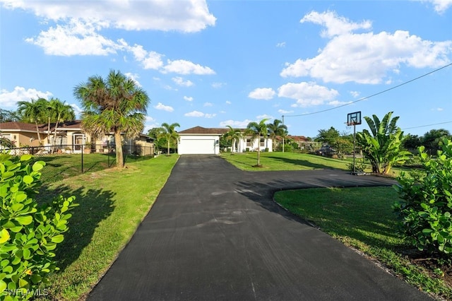 view of front of property with driveway, an attached garage, a front yard, and fence