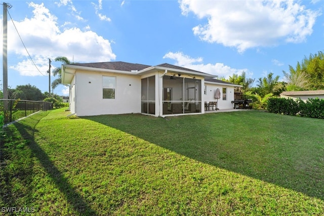 back of property featuring stucco siding, fence, a lawn, and a sunroom