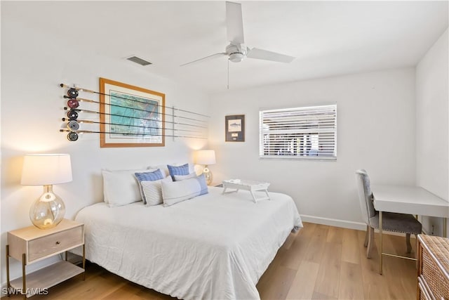 bedroom featuring ceiling fan, visible vents, baseboards, and wood finished floors