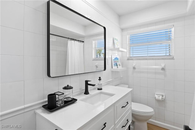 full bath featuring a shower with shower curtain, toilet, tile walls, and vanity