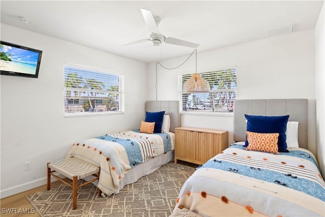 bedroom with visible vents, ceiling fan, baseboards, and wood finished floors