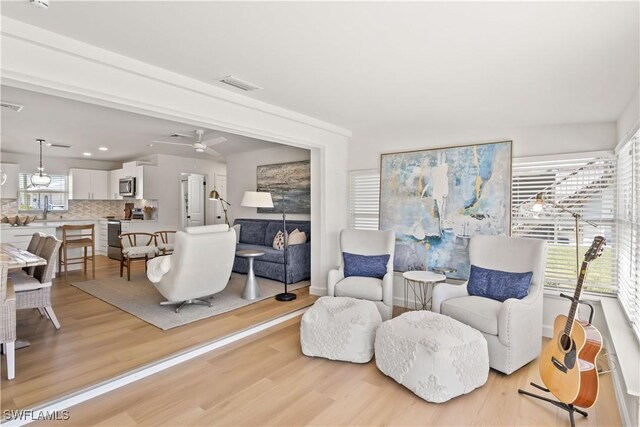 living room with visible vents, ceiling fan, and light wood-style floors