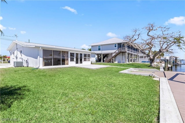 back of property featuring central air condition unit, a lawn, stairway, and a sunroom