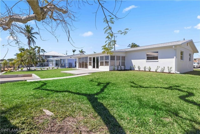 rear view of house featuring a yard, a patio, stucco siding, and a sunroom