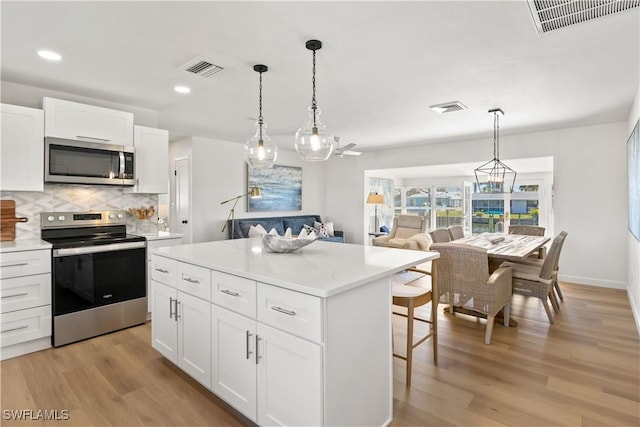 kitchen featuring light wood-type flooring, visible vents, a kitchen bar, and appliances with stainless steel finishes