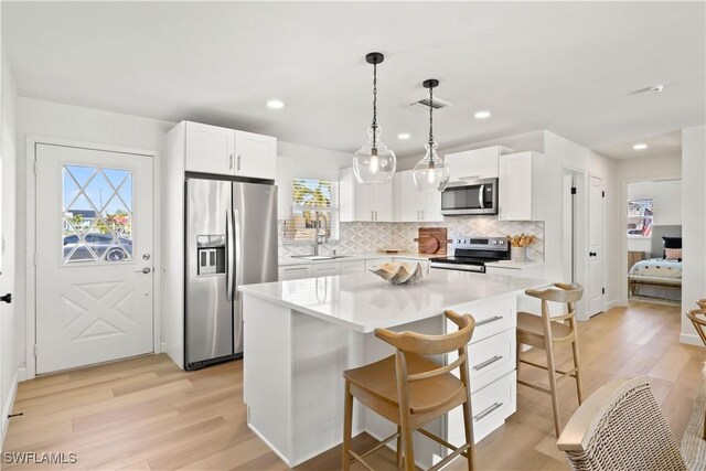 kitchen with a sink, a kitchen breakfast bar, light wood-style flooring, and stainless steel appliances