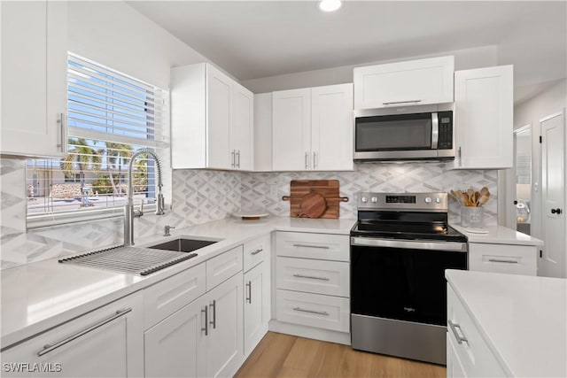 kitchen featuring white cabinetry, light countertops, appliances with stainless steel finishes, and a sink