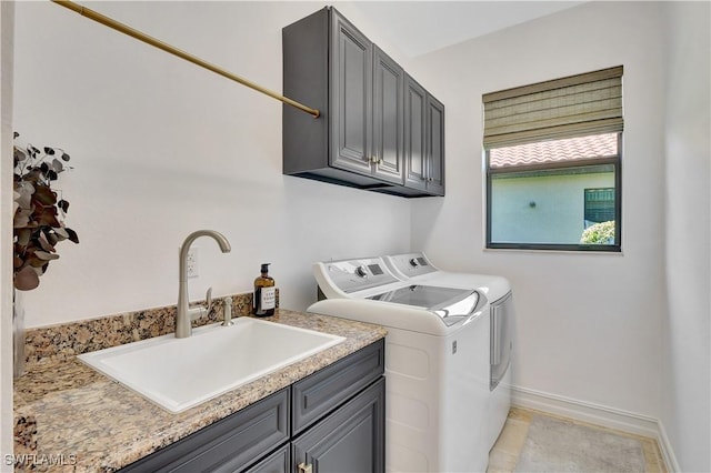 laundry area featuring washer and dryer, cabinet space, a sink, and baseboards