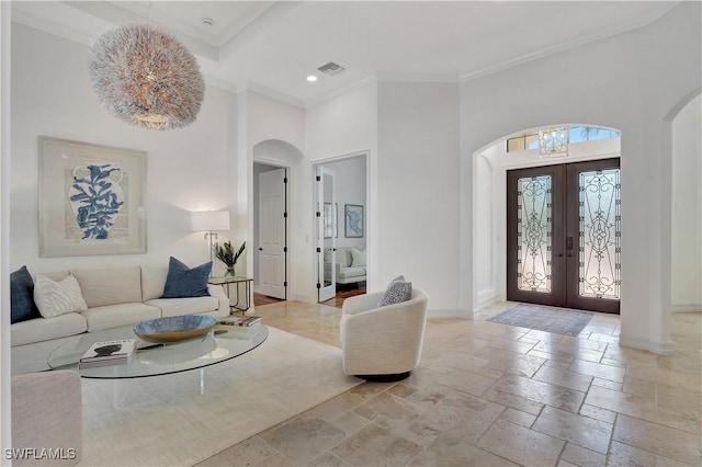 living area featuring arched walkways, stone tile flooring, baseboards, and french doors