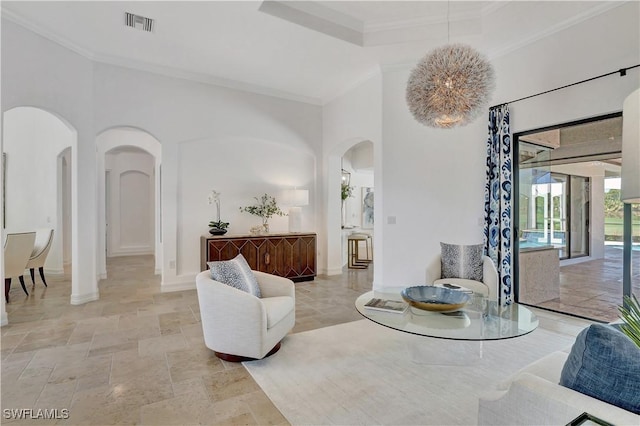 living area featuring ornamental molding, arched walkways, stone finish flooring, and baseboards