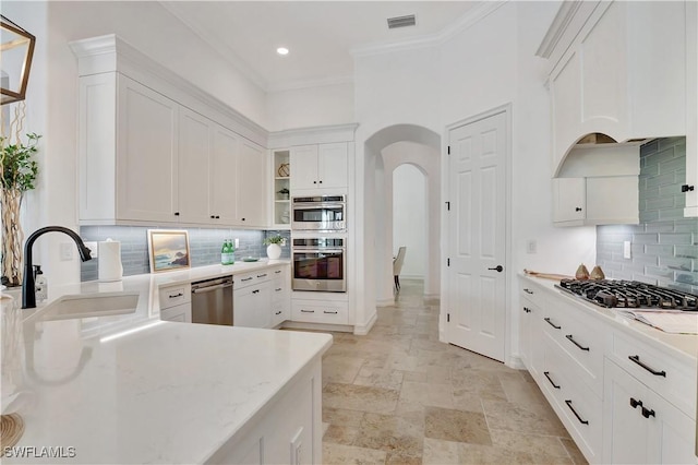 kitchen featuring white cabinetry, appliances with stainless steel finishes, arched walkways, and a sink