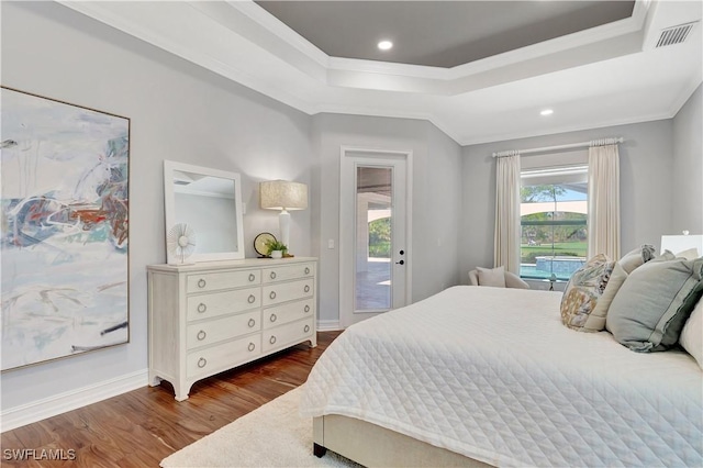 bedroom with dark wood-type flooring, visible vents, access to outside, a tray ceiling, and crown molding