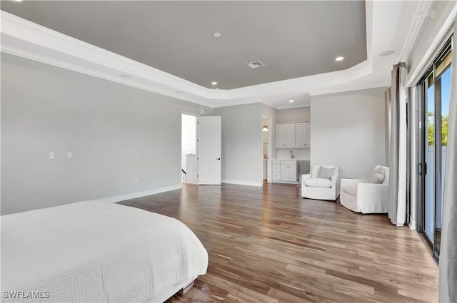 bedroom featuring crown molding, recessed lighting, a raised ceiling, wood finished floors, and baseboards