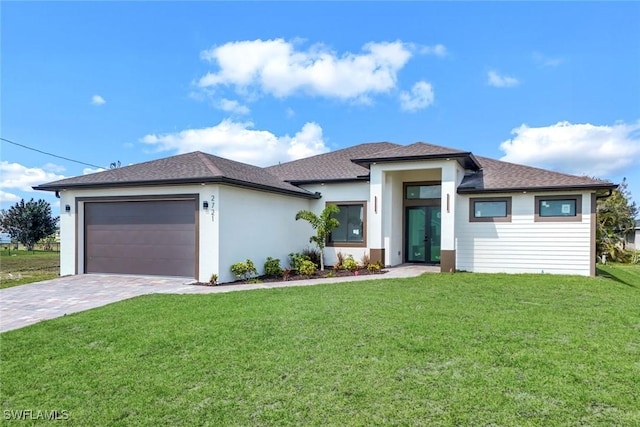 prairie-style home featuring an attached garage, french doors, decorative driveway, and a front lawn