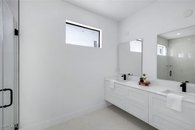 bathroom with double vanity, a shower stall, baseboards, and a sink