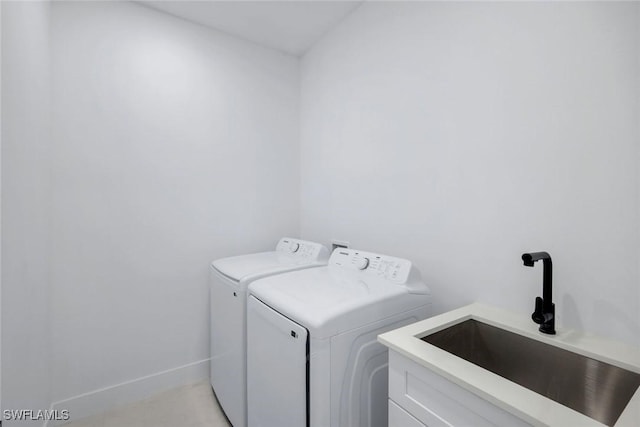 washroom with a sink, baseboards, cabinet space, and washing machine and dryer