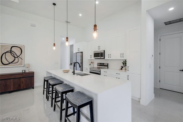 kitchen featuring visible vents, a breakfast bar, a sink, white cabinetry, and appliances with stainless steel finishes